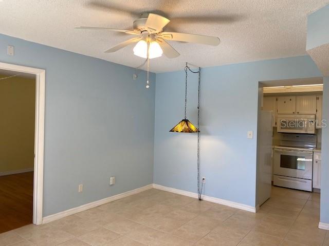 A dining area with light blue walls, tile flooring, a ceiling fan, and a pendant light — 19505 QUESADA AVENUE UNIT I202, PORT CHARLOTTE, FL