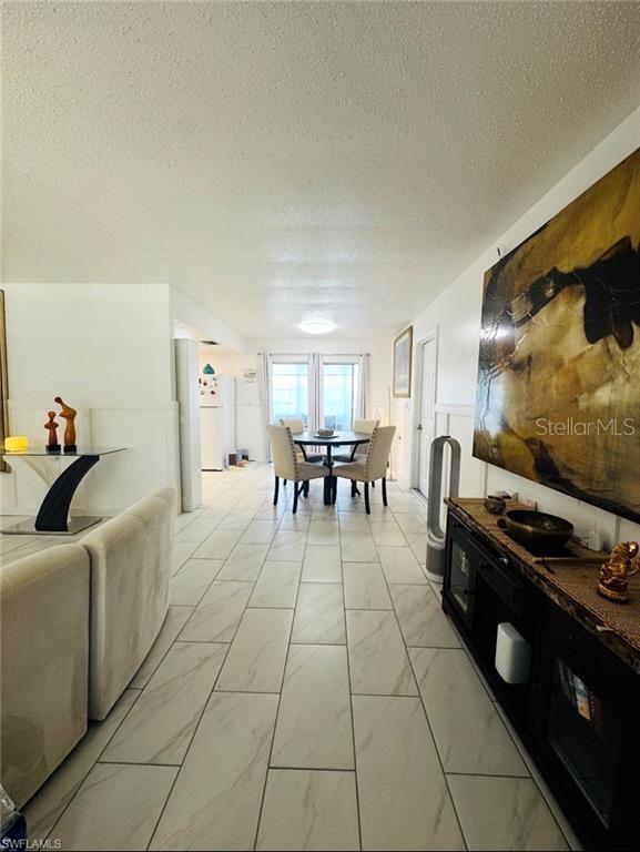 A living room and dining area feature light-colored tile flooring and a large abstract painting — 710 AQUI ESTA DRIVE, PUNTA GORDA, FL