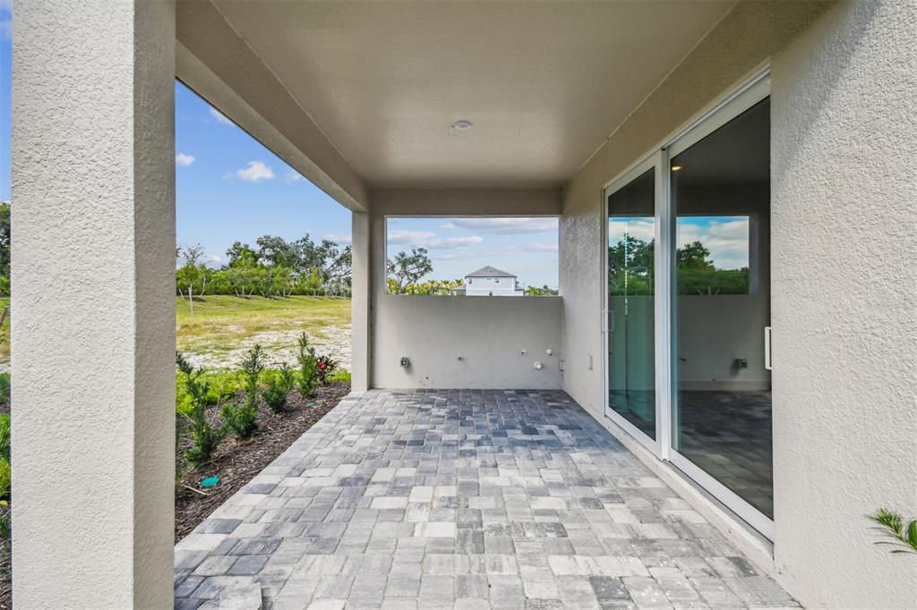 An open-concept kitchen and living area features white cabinetry, wood-look flooring, and sliding glass doors — 7571 HAWKSTONE DRIVE, SARASOTA, FL