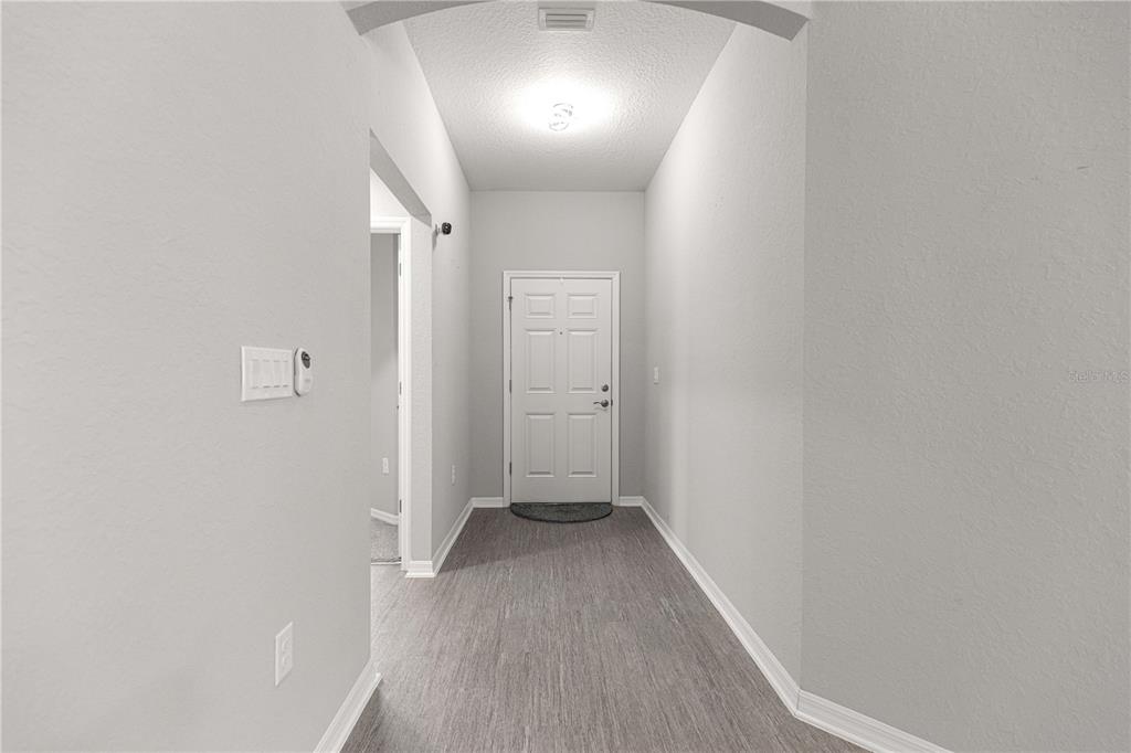 A bright entryway features light gray walls, wood-look flooring, and a white front door — 4720 SE 89TH PLACE ROAD, OCALA, FL