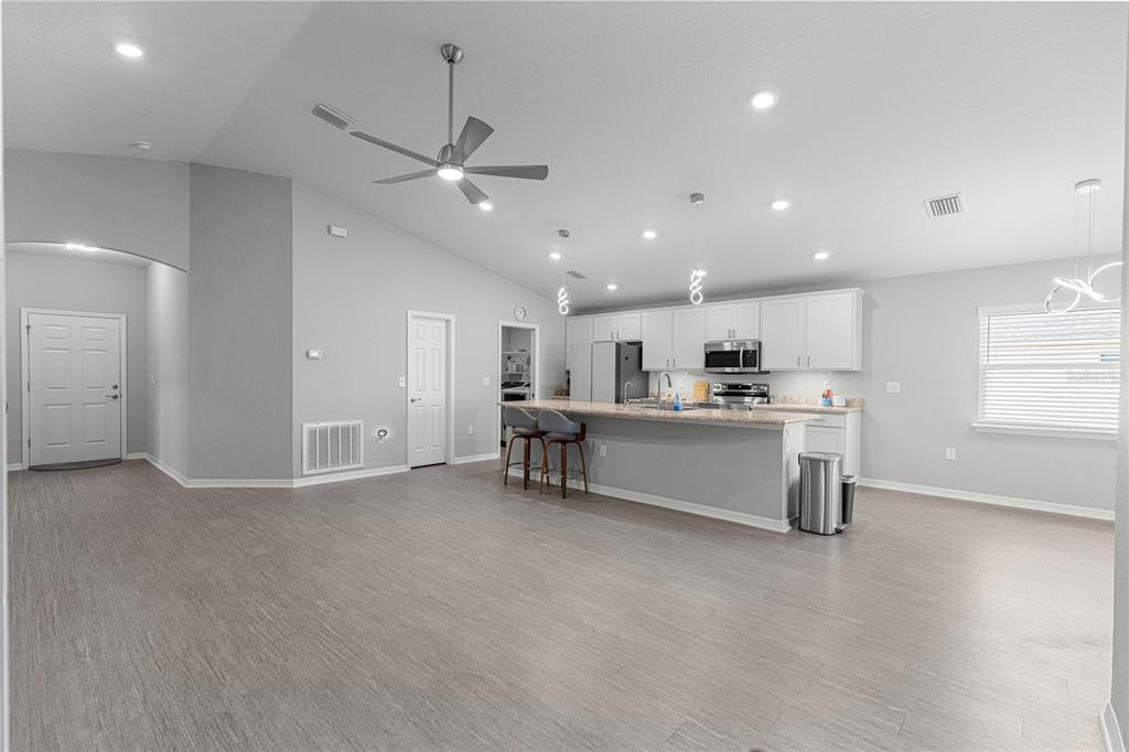 A spacious open-concept kitchen and living area with light gray flooring and white cabinetry — 4720 SE 89TH PLACE ROAD, OCALA, FL