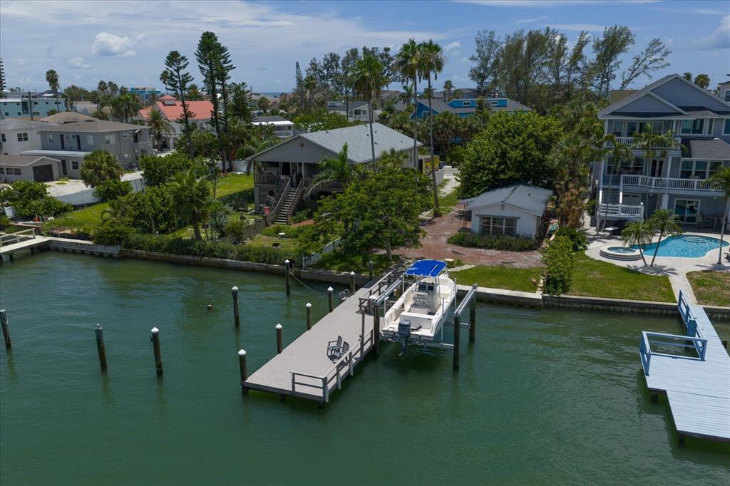 An aerial view of a waterfront property featuring a dock, a boat, and several houses — 8405 BAYSHORE DRIVE, TREASURE ISLAND, FL