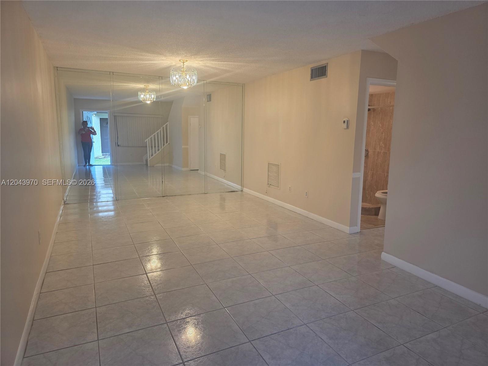 A tiled living area features a mirrored wall, a chandelier, and an adjacent bathroom — 4586 SW 139th Ct # 763, Miami FL 33175, MIAMI, FL