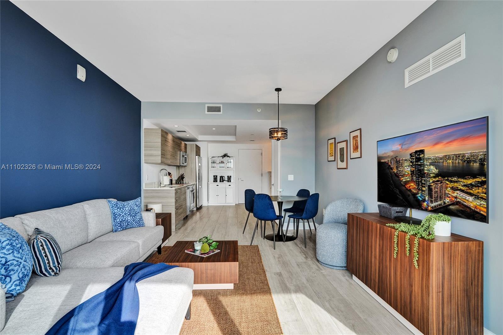 A living room and dining area feature a blue accent wall, wood flooring, and furniture — 121 NE 34th St # 2906, Miami FL 33137, MIAMI, FL