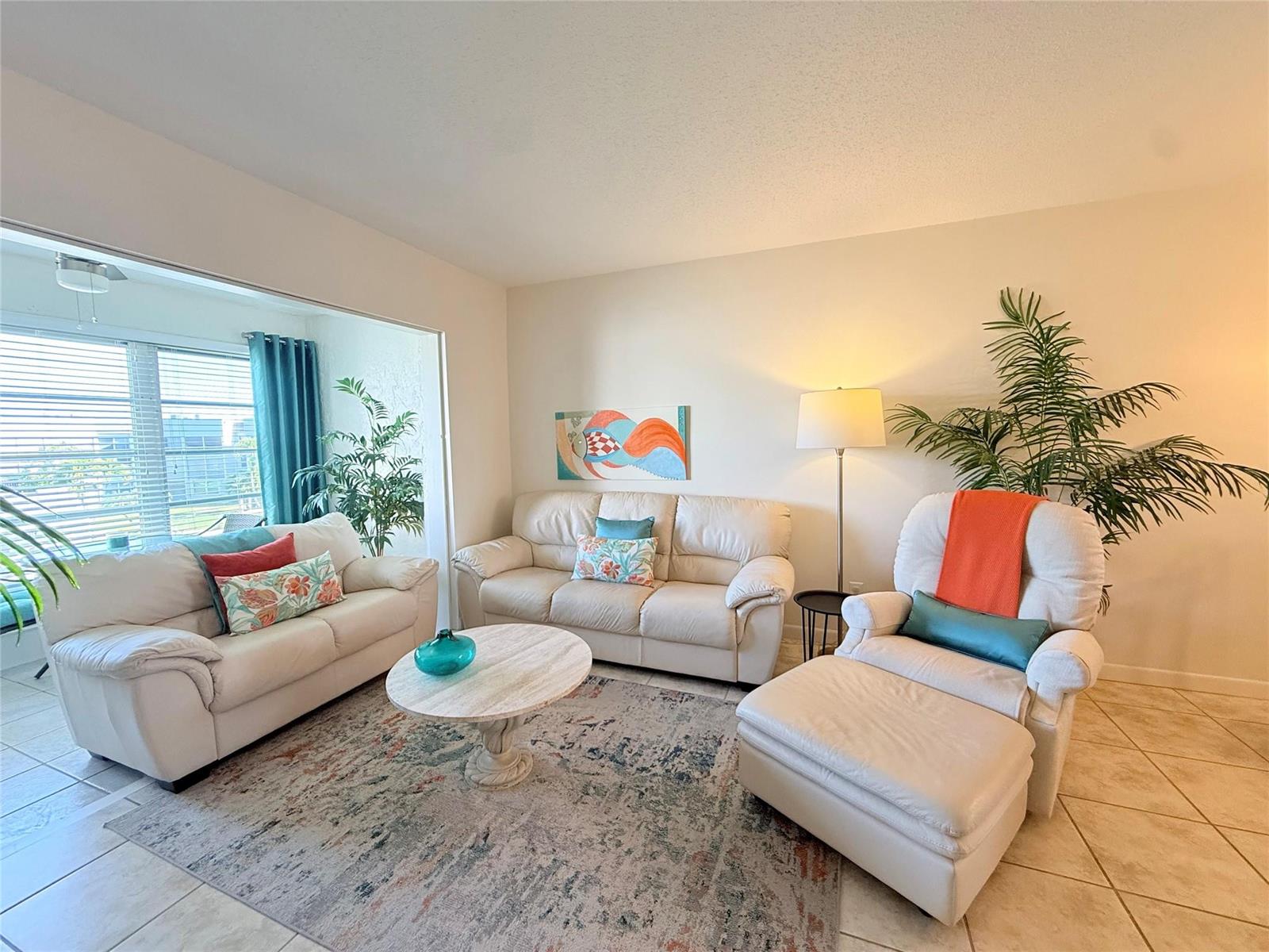 A living room features white leather furniture, a patterned area rug, and a floor lamp — 6650 Royal Palm Boulevard # C, Margate FL 33063, MARGATE, FL