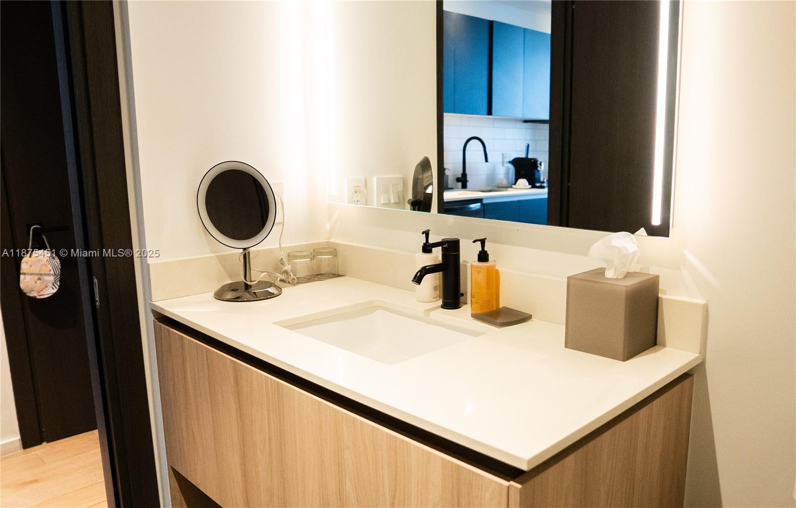 A modern bathroom vanity features a white countertop, black faucet, and a lighted mirror — 398 NE 5th St # 3612, Miami FL 33132, MIAMI, FL