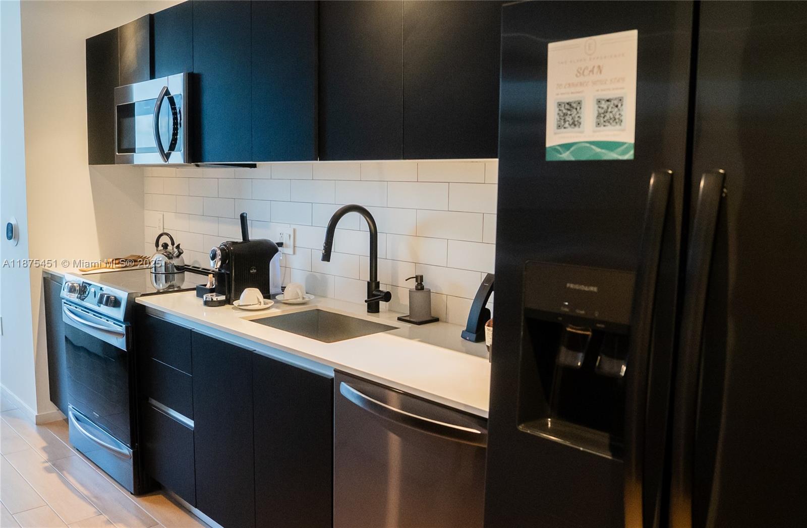 A modern kitchen features black cabinetry, stainless steel appliances, and a white subway tile backsplash — 398 NE 5th St # 3612, Miami FL 33132, MIAMI, FL