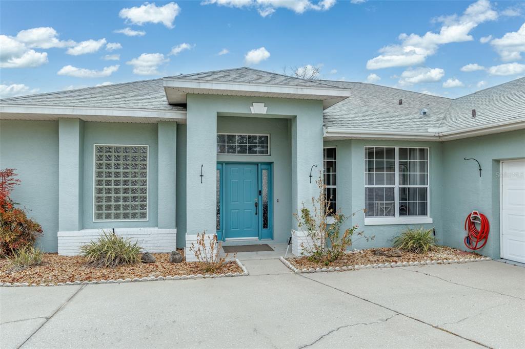 The exterior of a light green house features a blue front door and glass blocks — 4740 N CRESTLINE DRIVE, BEVERLY HILLS, FL
