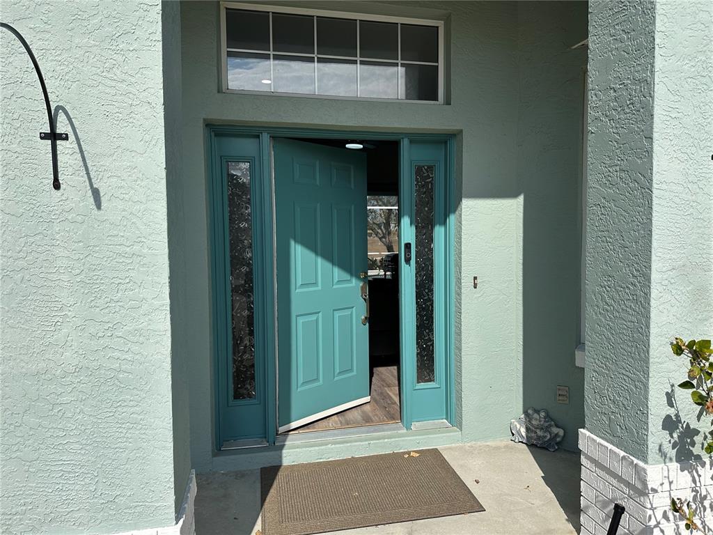 A teal front door with sidelights and a transom window sits under a covered porch — 4740 N CRESTLINE DRIVE, BEVERLY HILLS, FL