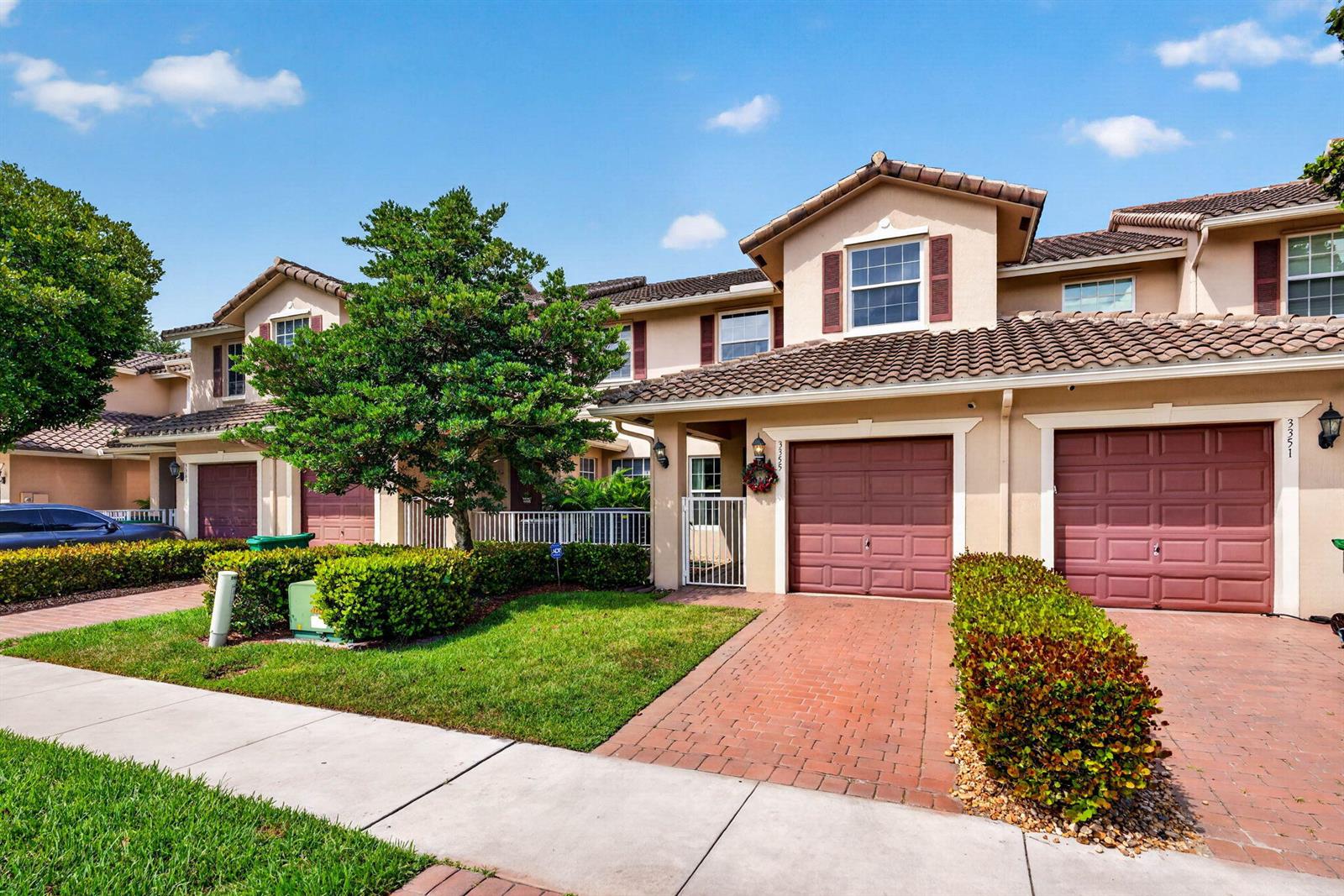 A two-story townhouse exterior features a brick driveway, two garage doors, and a small lawn — 3355 Lakeside Drive, Davie FL 33328, DAVIE, FL