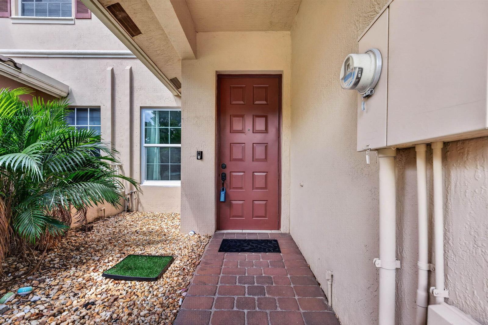 A red front door is centered on a paved walkway next to a gravel garden — 3355 Lakeside Drive, Davie FL 33328, DAVIE, FL