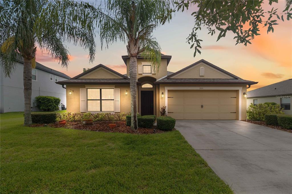 A single-story suburban house with a tan stucco exterior, a two-car garage, and palm trees — 3721 MARIETTA WAY, ST CLOUD, FL