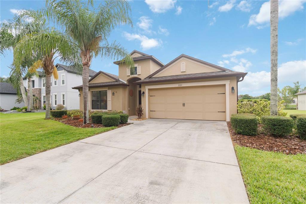 A tan single-story house with a two-car garage, palm trees, and a concrete driveway — 3721 MARIETTA WAY, ST CLOUD, FL