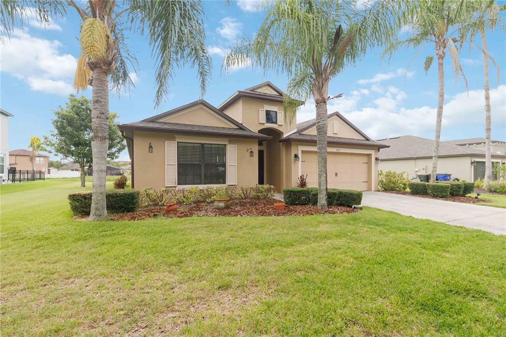 A tan, single-story suburban house with a two-car garage and palm trees in the front yard — 3721 MARIETTA WAY, ST CLOUD, FL