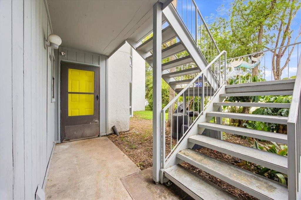 A concrete patio area features a brown door with a yellow screen and metal stairs — 2628 LEMON TREE LANE UNIT 6C, ORLANDO, FL