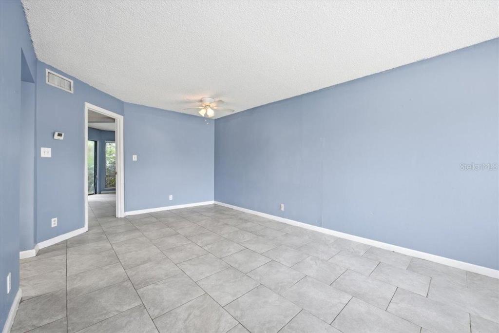A room with light blue walls, gray tile flooring, and a ceiling fan — 2628 LEMON TREE LANE UNIT 6C, ORLANDO, FL