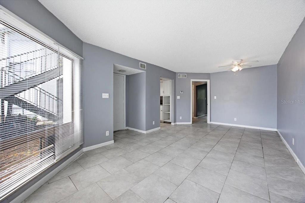 An empty room features gray walls, large light-colored floor tiles, and a window with blinds — 2628 LEMON TREE LANE UNIT 6C, ORLANDO, FL