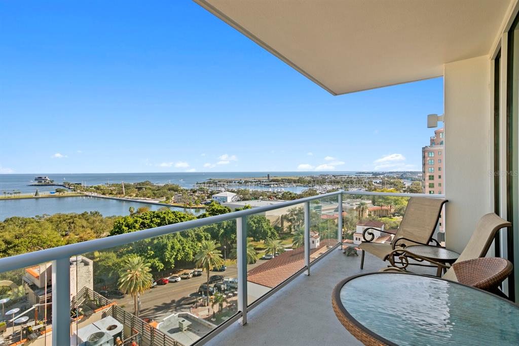 A high-rise balcony overlooks a marina, a park, and the ocean under a clear sky — 176 4TH AVENUE NE UNIT 1002, ST PETERSBURG, FL