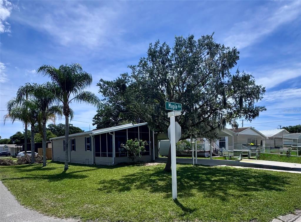 A single-story house with a screened porch sits on a grassy lot near a street sign — 4385 MAPLE AVENUE, EDGEWATER, FL
