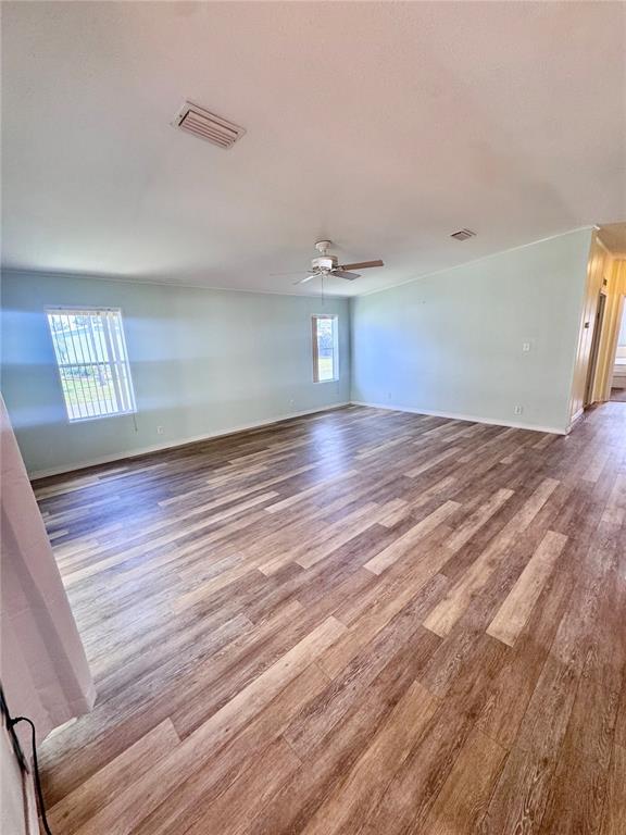 A spacious living room features light blue walls, a ceiling fan, and wood-look vinyl flooring — 4385 MAPLE AVENUE, EDGEWATER, FL