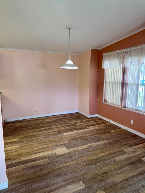 A dining area with wood-look flooring, a pendant light, and two-toned peach and orange walls — 4385 MAPLE AVENUE, EDGEWATER, FL
