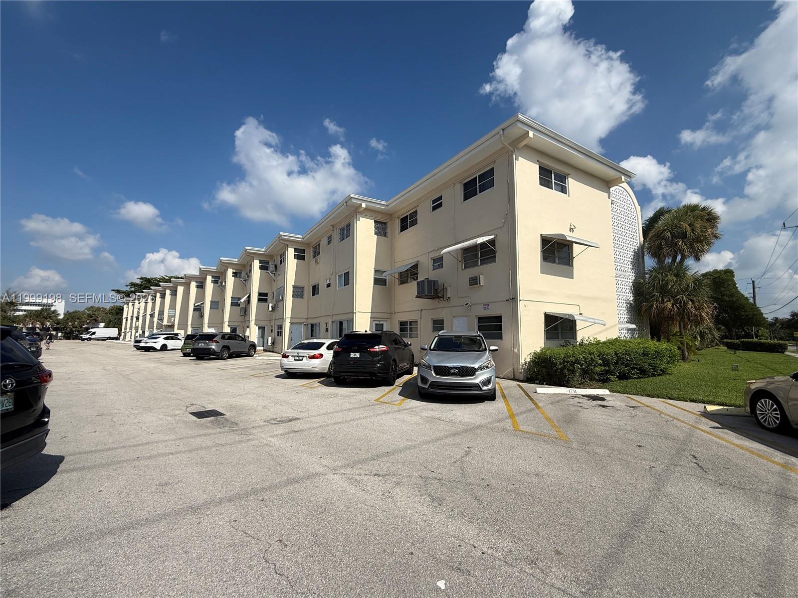 A multi-story apartment building with a parking lot in front under a blue sky — 141 NE 10th Ave # 17B, Hallandale Beach FL 33009, HALLANDALE BEACH, FL