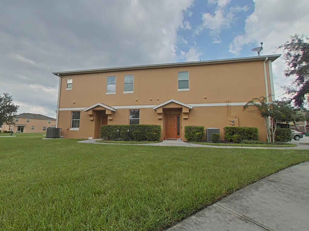 A two-story tan stucco townhouse with two front entrances and a grassy lawn — 15625 BOGGY OAK CIRCLE UNIT 108B, WINTER GARDEN, FL