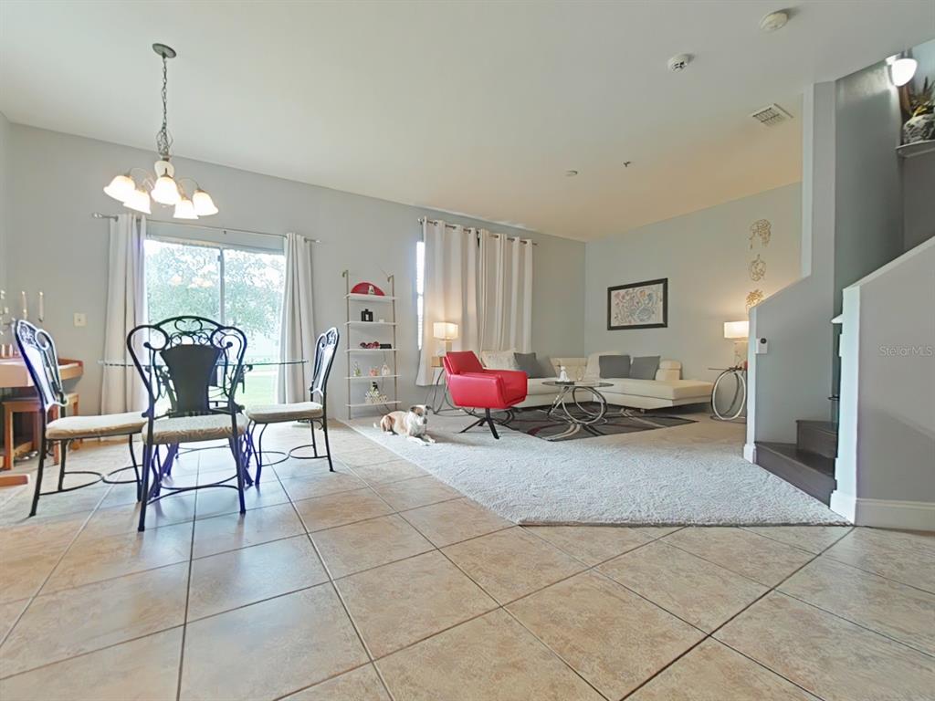 A living and dining area features tile flooring, a red accent chair, and a dog — 15625 BOGGY OAK CIRCLE UNIT 108B, WINTER GARDEN, FL