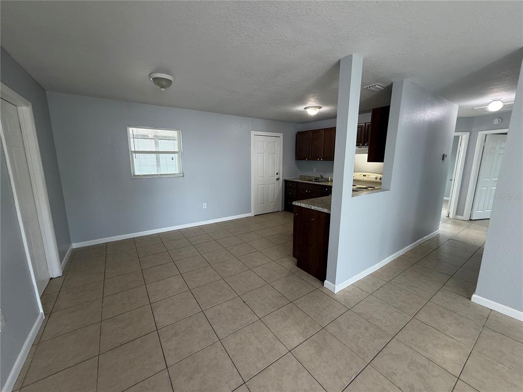 An open-concept kitchen and dining area features light blue walls, tile flooring, and dark cabinetry — 613 CARVER DRIVE, LAKE WALES, FL