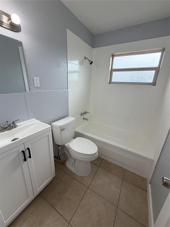 A bathroom features a white vanity, a toilet, and a bathtub with a shower head — 613 CARVER DRIVE, LAKE WALES, FL