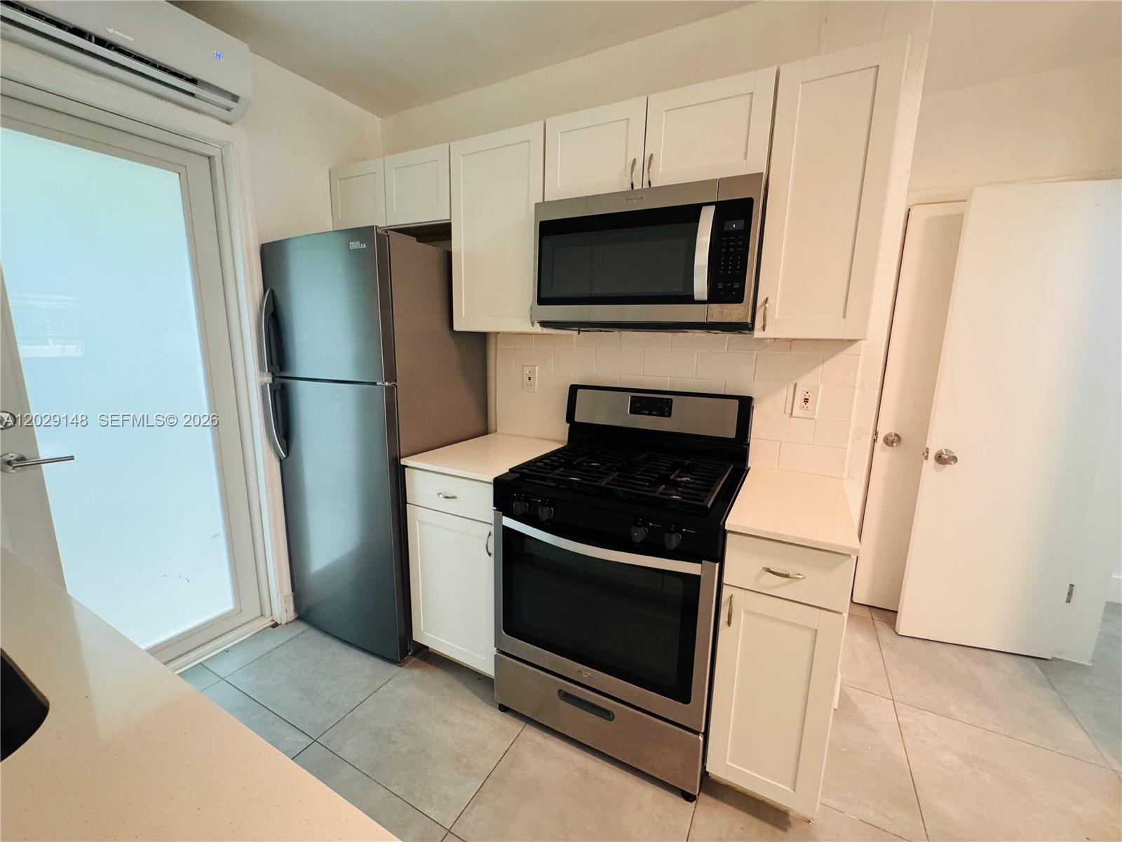 A kitchen features white cabinets, stainless steel appliances, and light-colored tile flooring — 75 Washington Ave # 10, Miami Beach FL 33139, MIAMI BEACH, FL