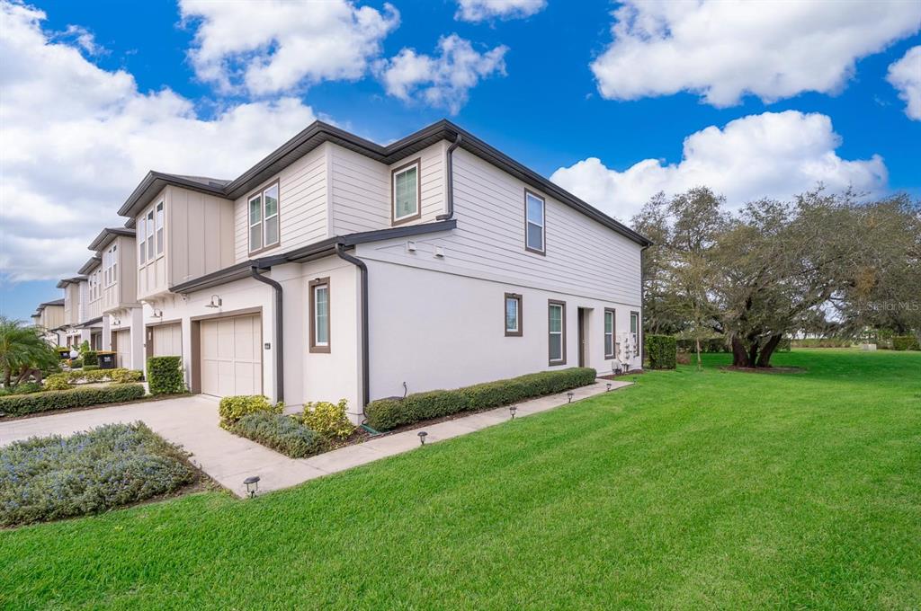 A two-story townhouse with a beige exterior, a one-car garage, and a side lawn — 664 BENOI DRIVE, DAVENPORT, FL