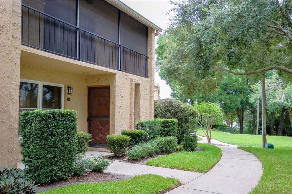 A two-story tan stucco building features a screened balcony and a ground-level entrance — 812 PARK LAKE CIRCLE UNIT 7, MAITLAND, FL