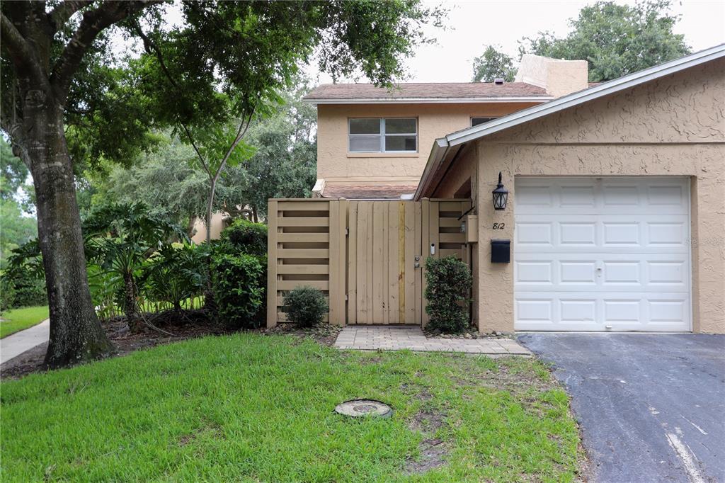 A brown screen door leads to a covered entryway overlooking a grassy lawn and trees — 812 PARK LAKE CIRCLE UNIT 7, MAITLAND, FL