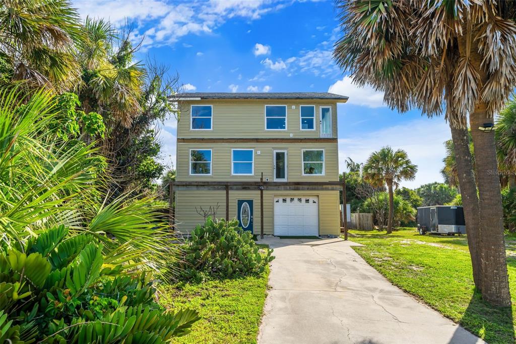 A three-story, light green house with a garage and a concrete driveway surrounded by palm trees — 6850 S HIGHWAY A1A, MELBOURNE BEACH, FL