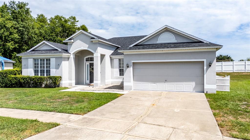 A single-story house with a gray stucco exterior, a two-car garage, and a concrete driveway — 3058 BAY LAUREL CIRCLE N, KISSIMMEE, FL