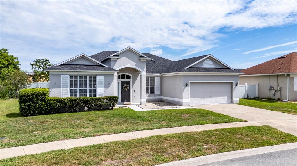 A single-story house with a gray stucco exterior, dark roof, and an attached two-car garage — 3058 BAY LAUREL CIRCLE N, KISSIMMEE, FL