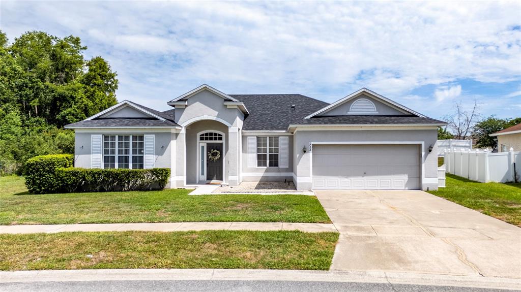 A single-story house with a gray exterior, a two-car garage, and a front lawn — 3058 BAY LAUREL CIRCLE N, KISSIMMEE, FL