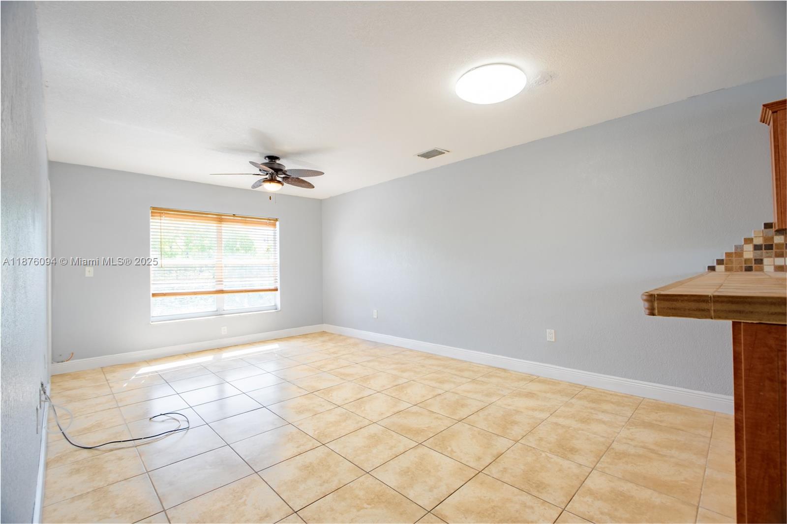 An empty room features light gray walls, beige tile flooring, a ceiling fan, and a window — 120 Royal Palm Rd # 315, Hialeah Gardens FL 33016, HIALEAH GARDENS, FL
