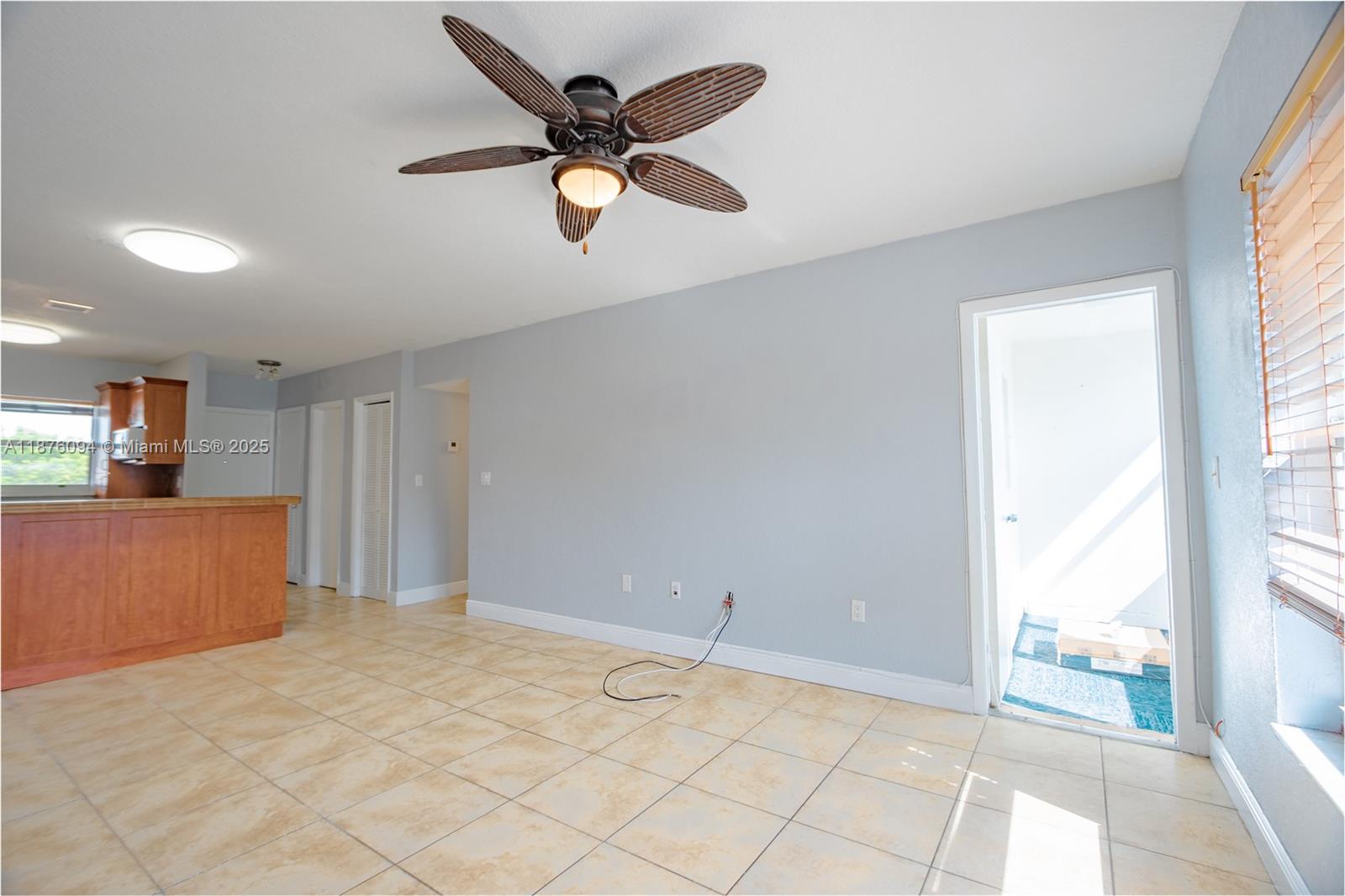 This living area features light-colored tile flooring, a ceiling fan, and an adjacent kitchen — 120 Royal Palm Rd # 315, Hialeah Gardens FL 33016, HIALEAH GARDENS, FL