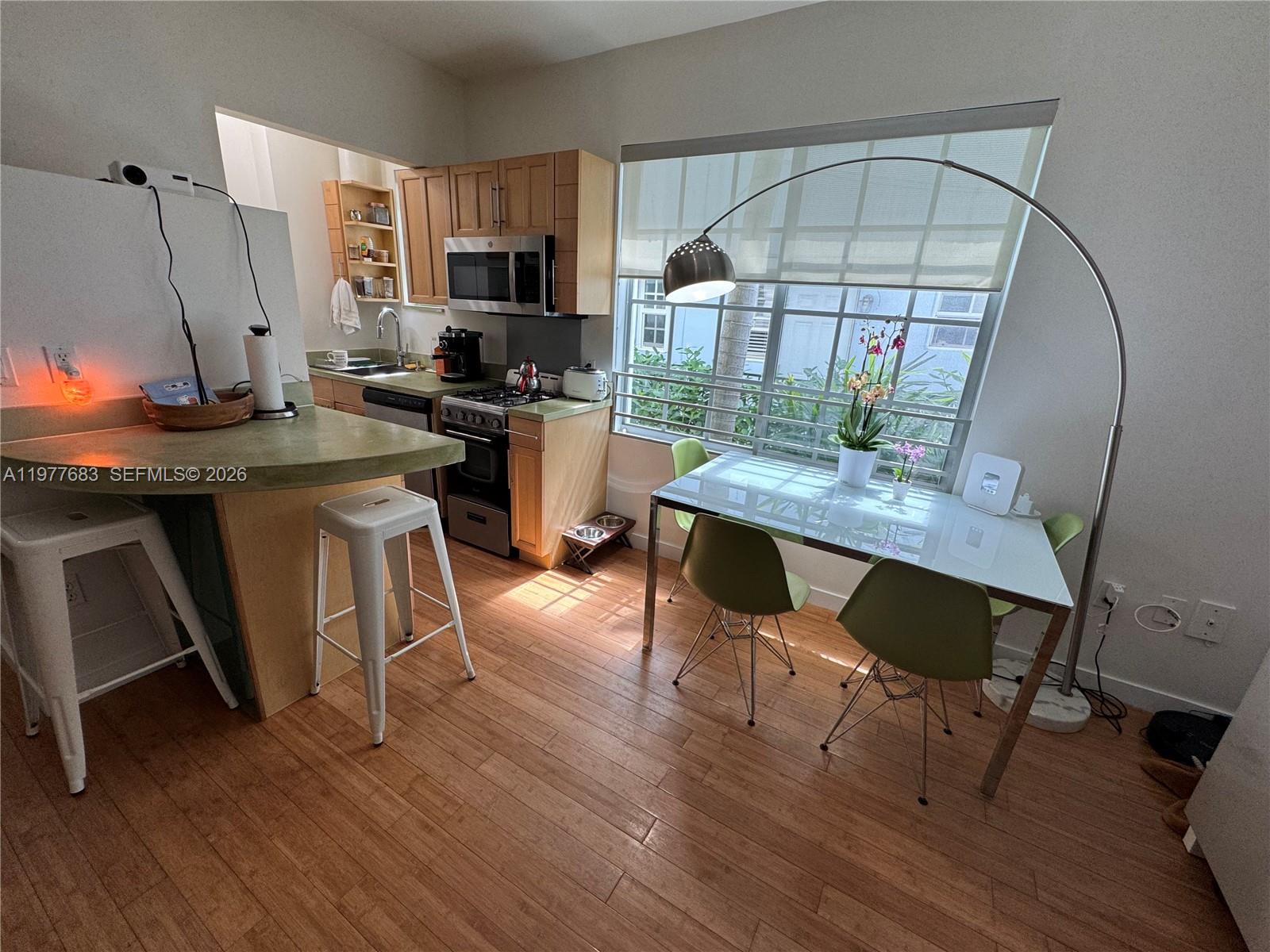 A kitchen features light wood cabinets, a breakfast bar, and a dining area with chairs — 815 Euclid Ave # 7, Miami Beach FL 33139, MIAMI BEACH, FL