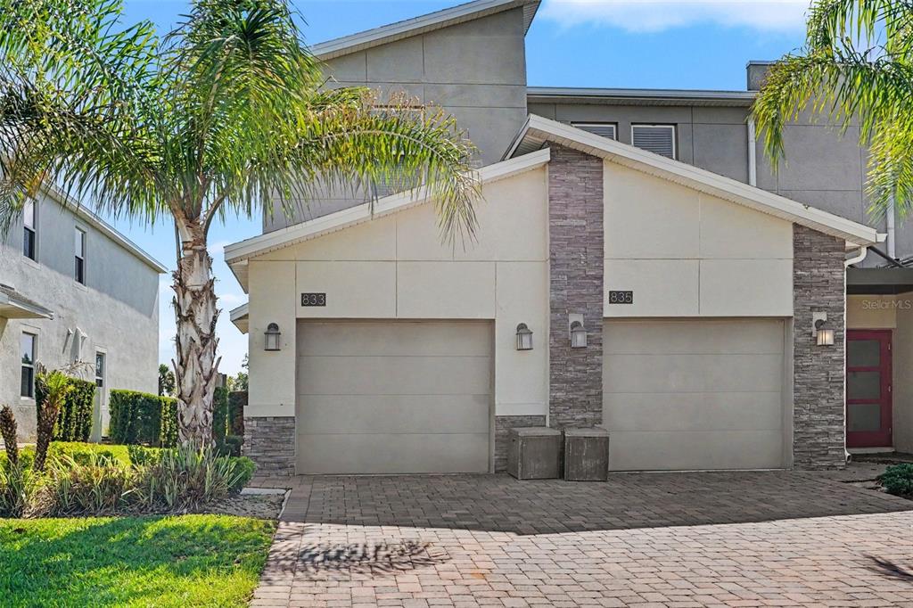 A two-story duplex with beige stucco walls, stone accents, and two garage doors — 833 OCEAN COURSE AVENUE UNIT 833, DAVENPORT, FL