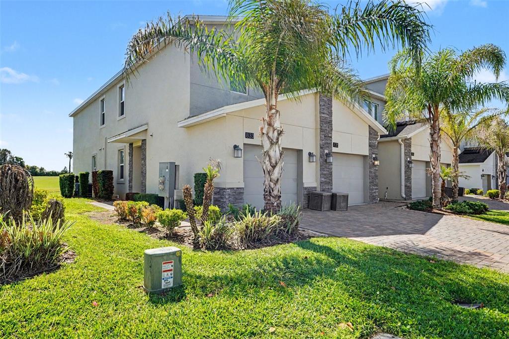 A two-story townhouse with a beige stucco exterior, stone accents, and a paved driveway — 833 OCEAN COURSE AVENUE UNIT 833, DAVENPORT, FL