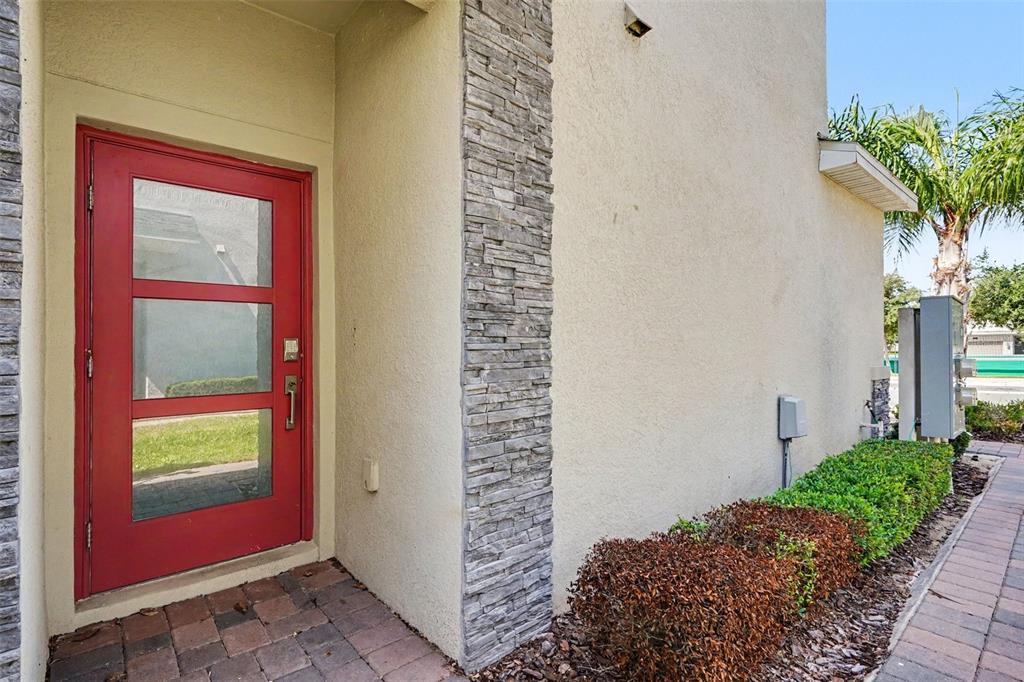 A red front door with glass panels sits next to a stone-accented exterior wall — 833 OCEAN COURSE AVENUE UNIT 833, DAVENPORT, FL