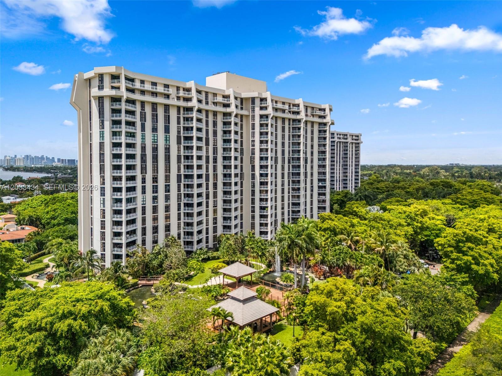 An aerial view shows a tall residential building surrounded by lush trees and garden gazebos — 1000 QUAYSIDE TER # 1604, Miami FL 33138, MIAMI, FL