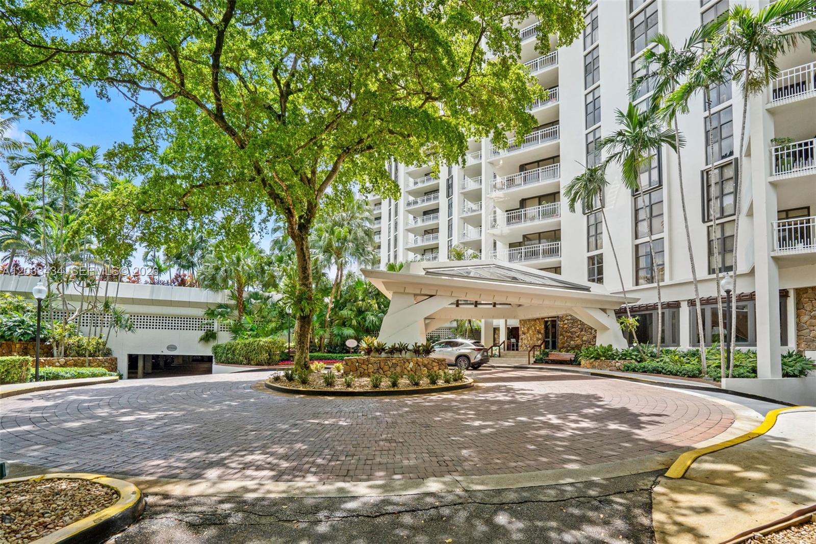 A circular brick driveway leads to the covered entrance of a multi-story white apartment building — 1000 QUAYSIDE TER # 1604, Miami FL 33138, MIAMI, FL