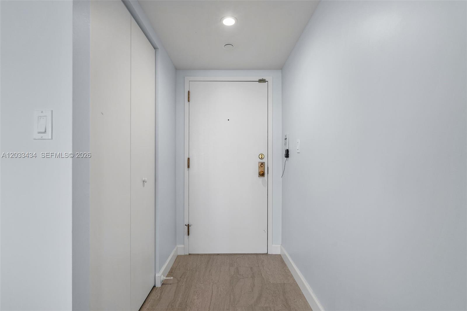 A narrow entryway features light blue walls, a white door, and wood-look tile flooring — 1000 QUAYSIDE TER # 1604, Miami FL 33138, MIAMI, FL