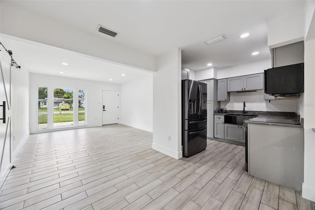 An open-concept living area features light wood-look tile floors and a modern gray kitchen — 204 W BUCHANON AVENUE, ORLANDO, FL