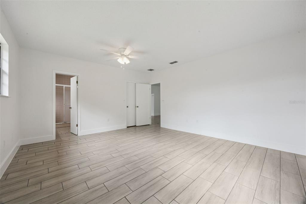 A spacious bedroom with white walls, a ceiling fan, and light-colored wood-look tile flooring — 204 W BUCHANON AVENUE, ORLANDO, FL