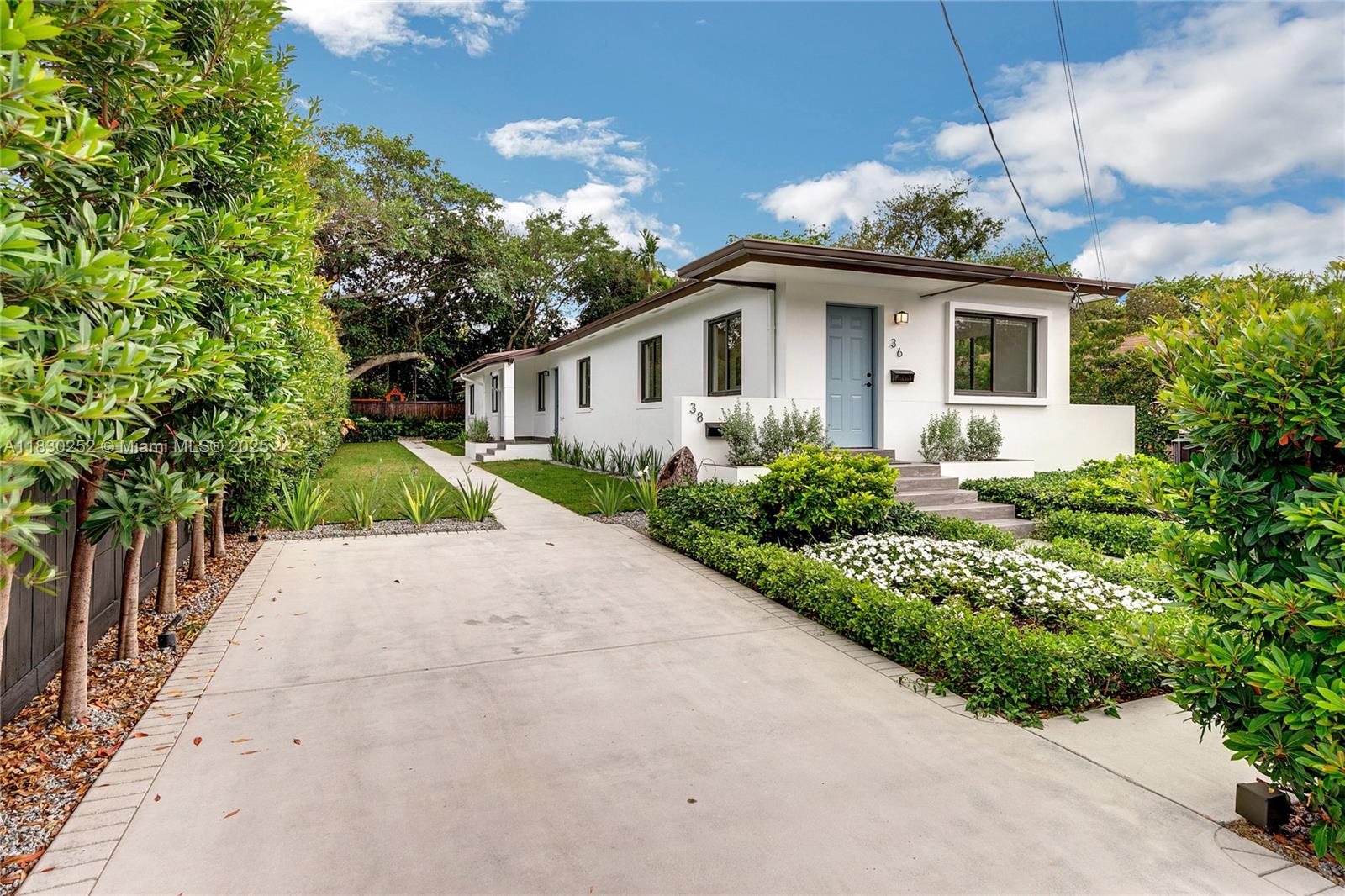 A white single-story house with a blue front door and a concrete driveway — 36 NW 52nd St, Miami FL 33127, MIAMI, FL